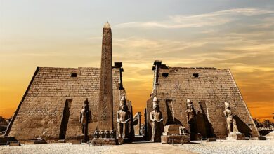 Entrance to the Luxor Temple at sunset showing the obelisk and statues of pharaohs