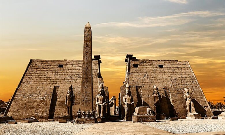 Entrance to the Luxor Temple at sunset showing the obelisk and statues of pharaohs