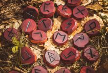Red runes carved from wood on the ground. There are 24 runes in the Elder Futhark.