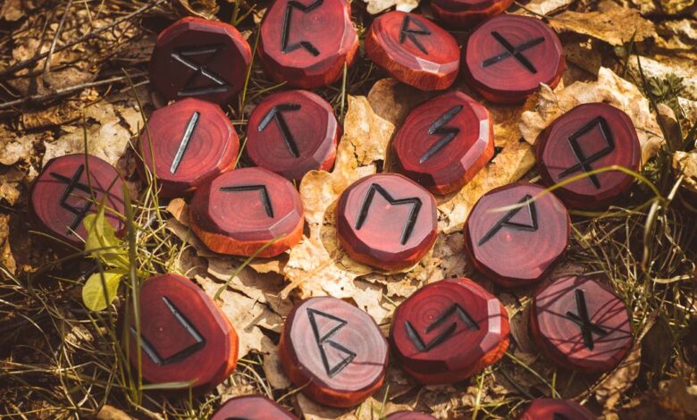 Red runes carved from wood on the ground. There are 24 runes in the Elder Futhark.