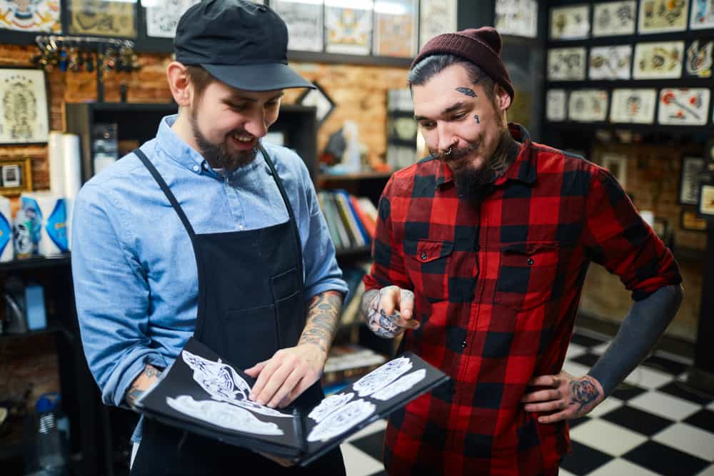 Un maître du tatouage aide son client à choisir son ornement