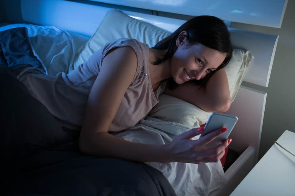 femme au lit avec un téléphone portable